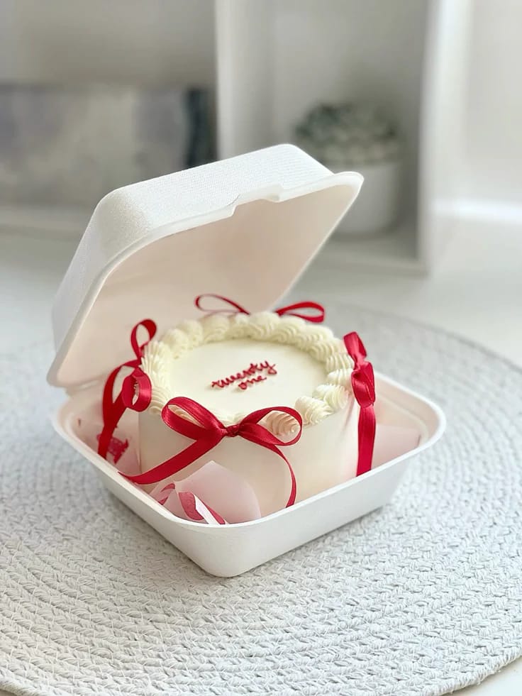 Mini ivory bento cake with a piped shell border and red satin ribbon bows, a 21st birthday bento cake gift in Bahrain.