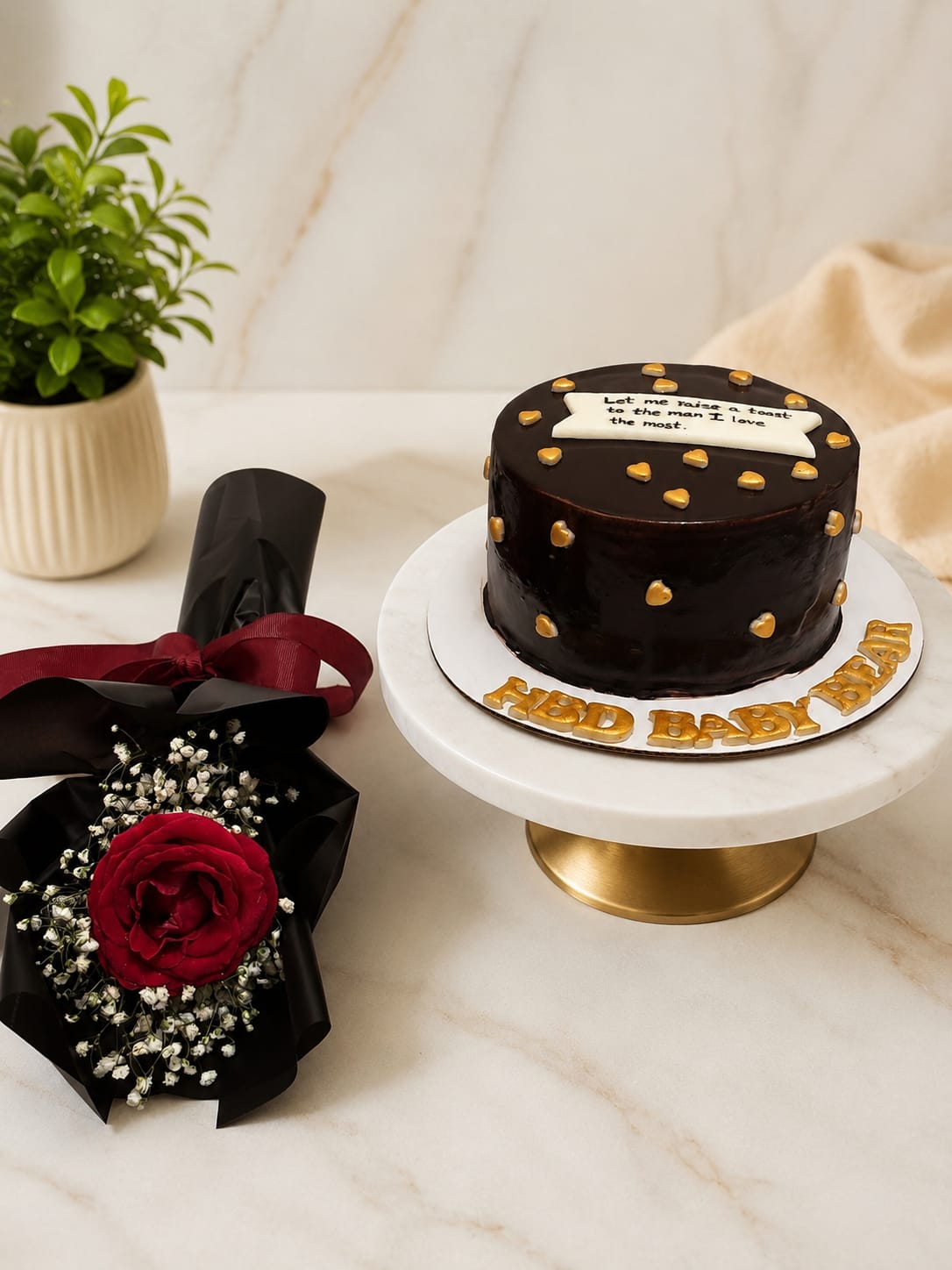Glossy dark chocolate drip cake with gold heart accents paired with a dark red rose bouquet wrapped in black paper and ribbon, a romantic flower and cake gift set in Bahrain.
