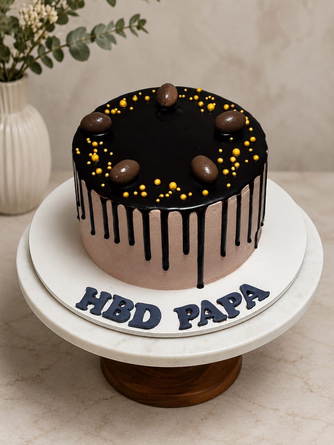 Chocolate buttercream cake with a black chocolate drip, gold sugar pearls and chocolate bonbons, a CakeCanva chocolate cake design in Bahrain.