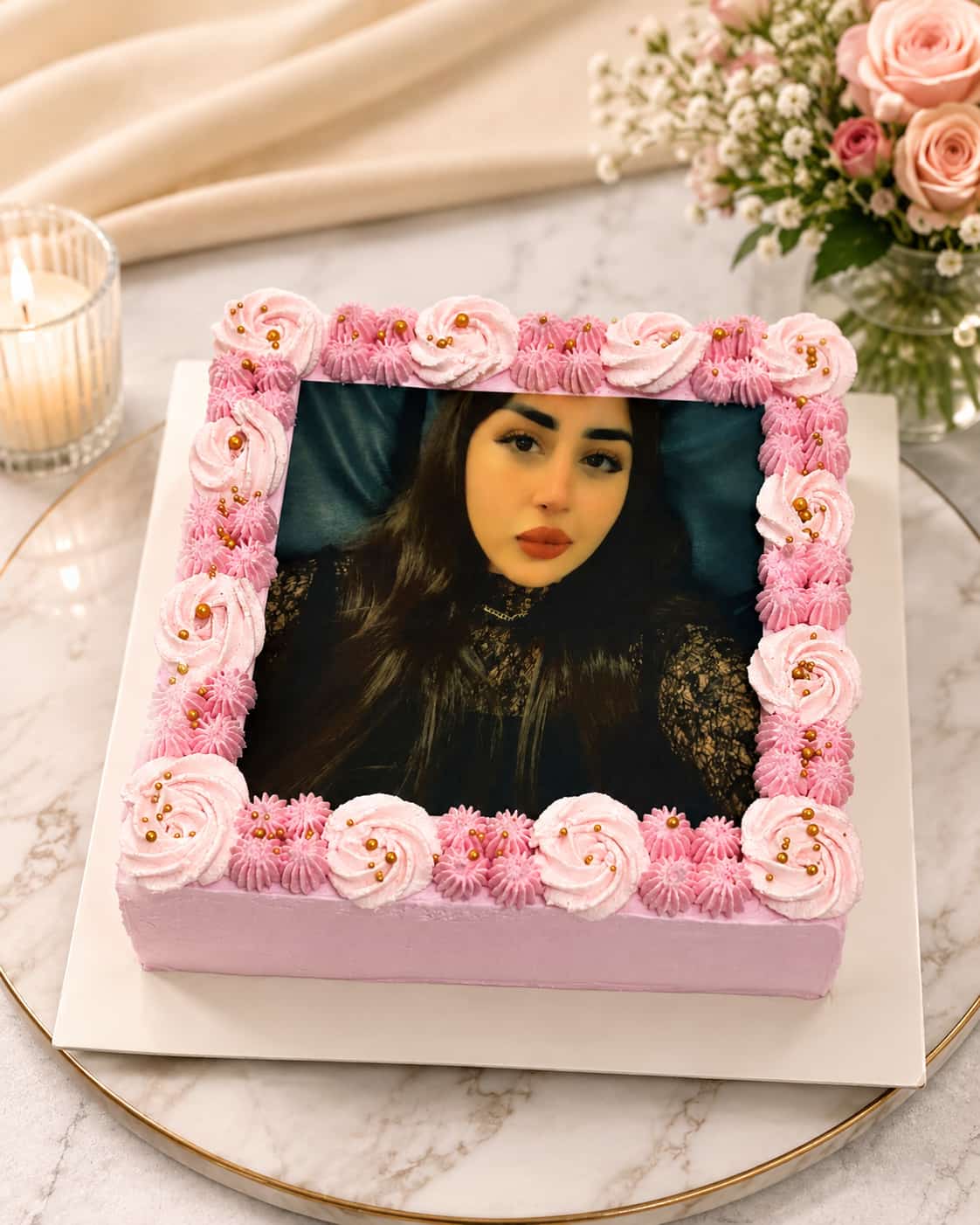 Square lilac and pink cake edged with piped cream rosettes and gold sugar pearls, framing a large edible portrait photo print, a birthday photo cake in Bahrain.
