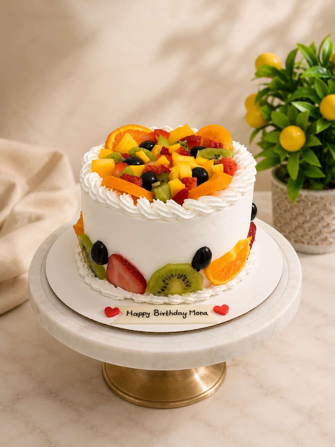 White whipped cream birthday cake topped with fresh strawberries, kiwi, orange, mango and grapes, by CakeCanva in Bahrain.