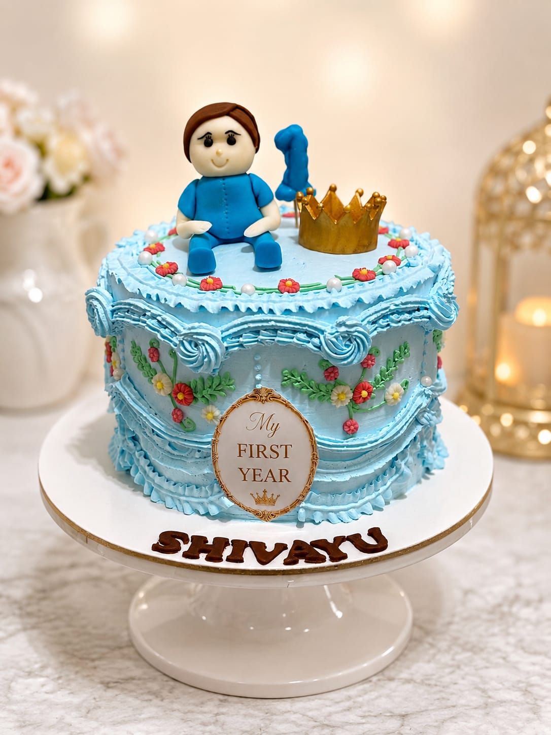 Blue vintage Lambeth first birthday cake with a baby-boy figure and gold crown by CakeCanva in Bahrain.