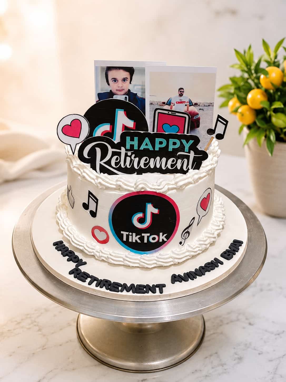 White buttercream retirement cake with a TikTok logo, music notes and heart cutouts, a 'Happy Retirement' topper and two edible photo prints, personalized 'Happy Retirement Avinash Bhai' in Bahrain.